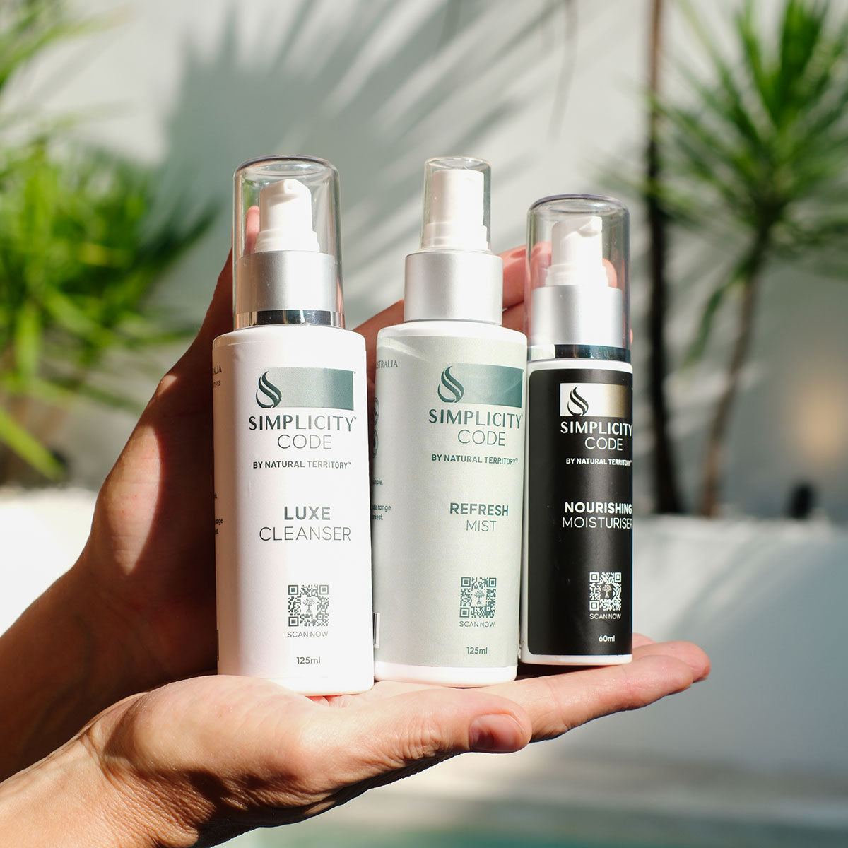 Three skincare products from Simplicity Code held in a hand with a blurred natural background